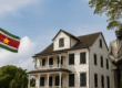 Historisch gebouw in Paramaribo met de Surinaamse vlag en standbeeld, symbool voor de rijke cultuur en geschiedenis van Suriname.